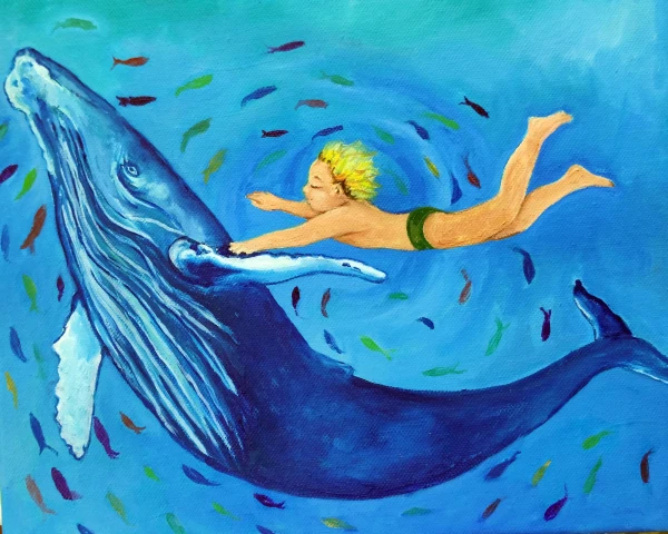 a child swims holding onto the fin of a humpback whale